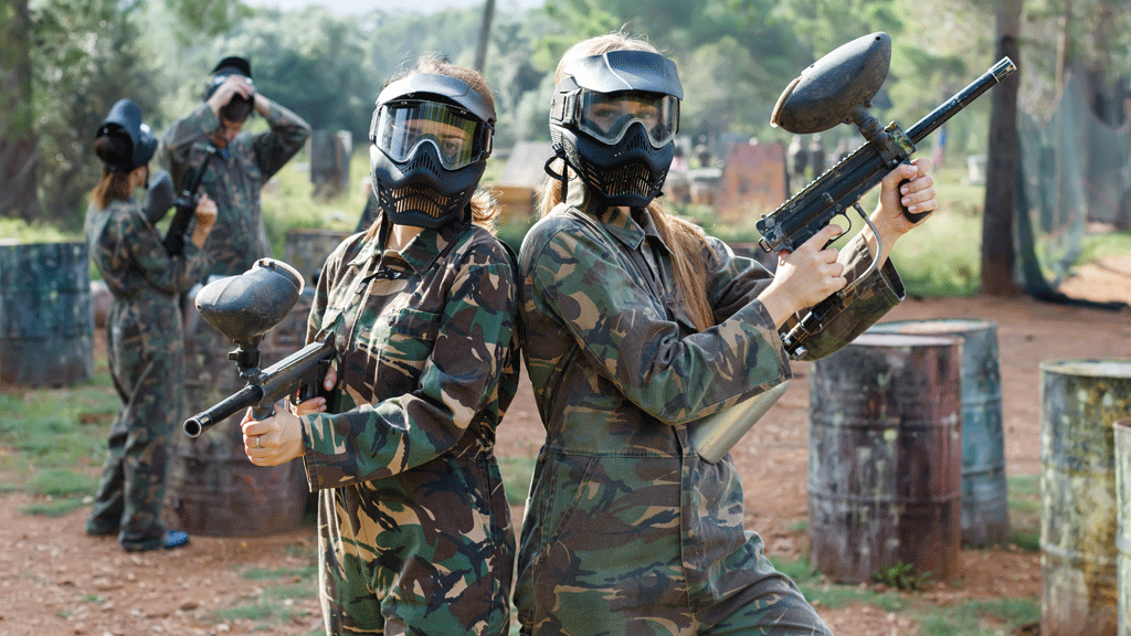 Deux collègues en tenue de paintball échangeant sur leur stratégie de jeu lors d'un team building